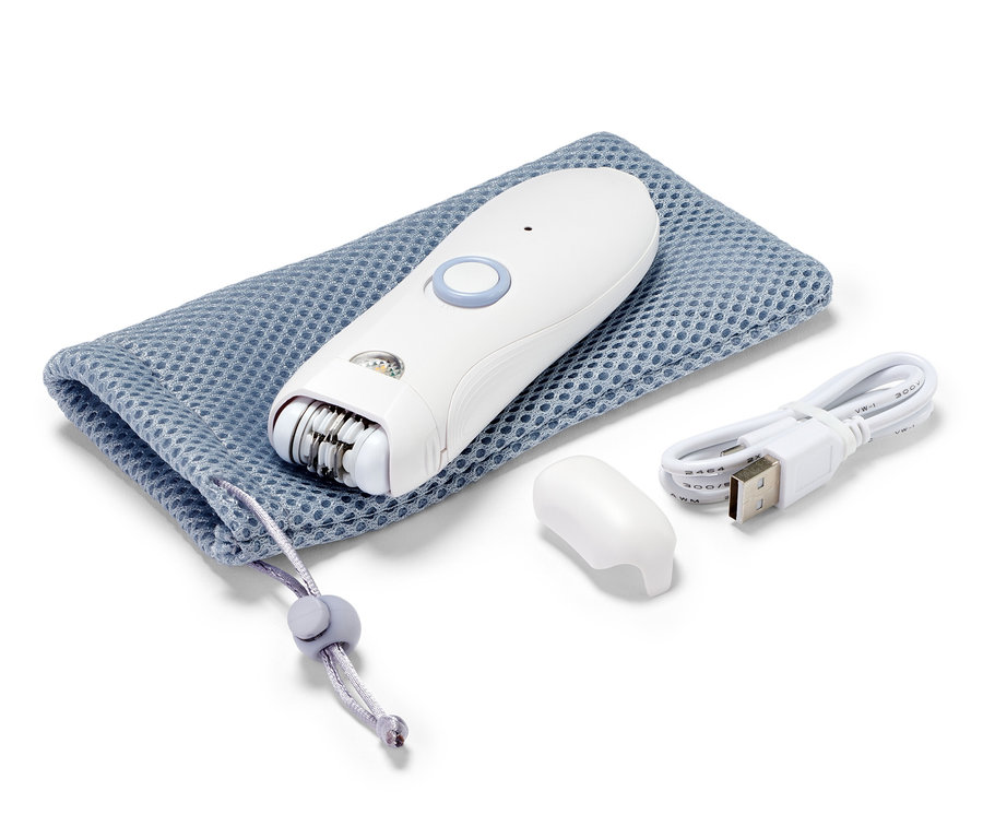 Ein weißer Gesichtsepilierer liegt auf einem blauen Kordelzugbeutel neben einem Ladekabel und einer Kappe.