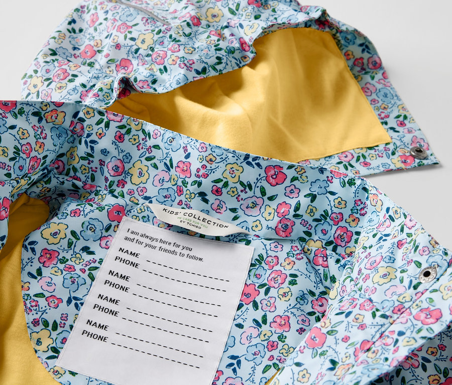 Detailansicht einer Kinder-Regenjacke mit Blumenmuster und gelbem Futter.