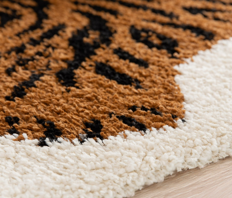 Detailansicht des Kinderteppichs NOMAD Tiger mit braunen und schwarzen Tigerstreifen und weißem Rand.