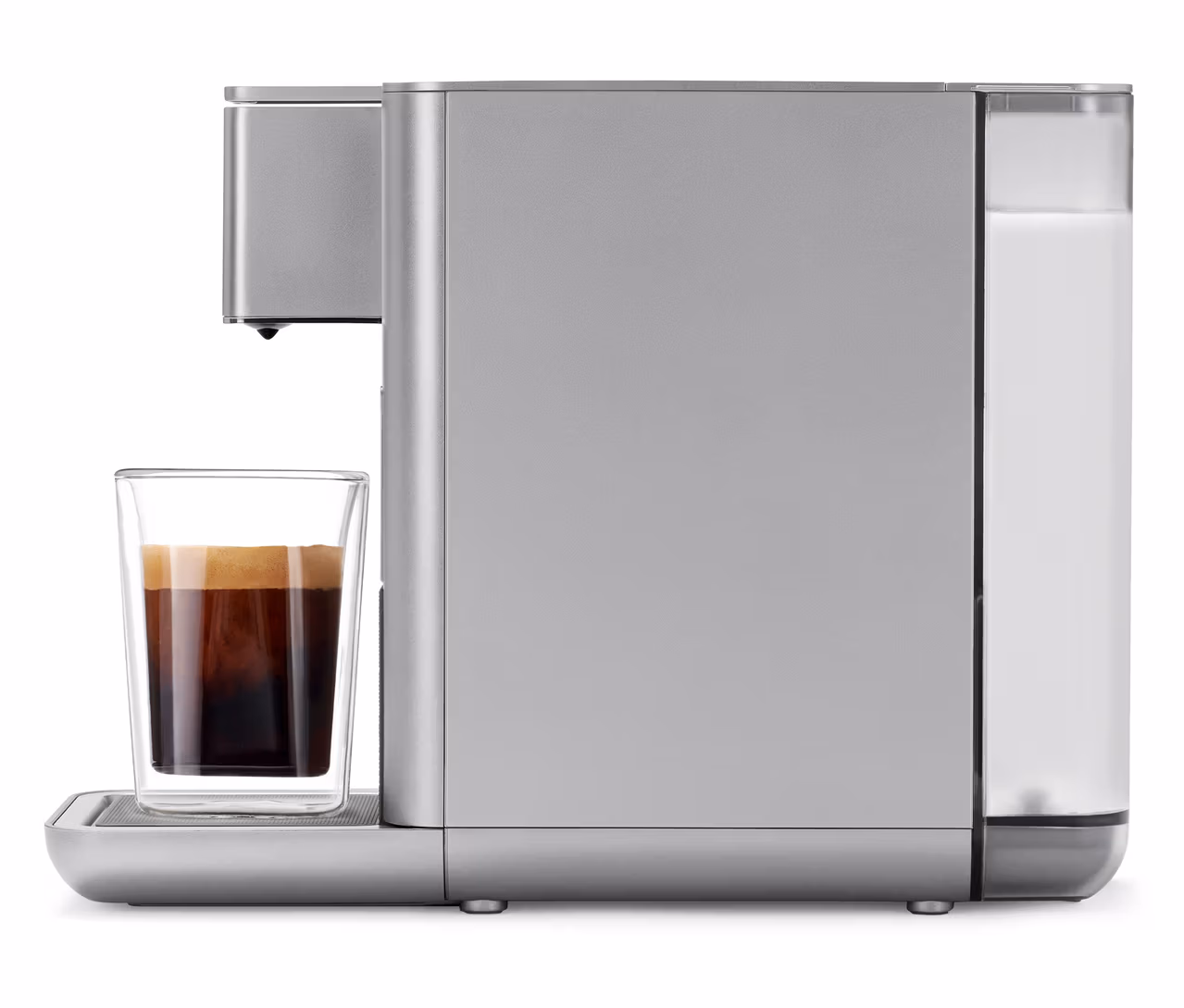 Qbo ICONIC Kaffeemaschine in Frozen Silver mit einem Glas Kaffee davor.