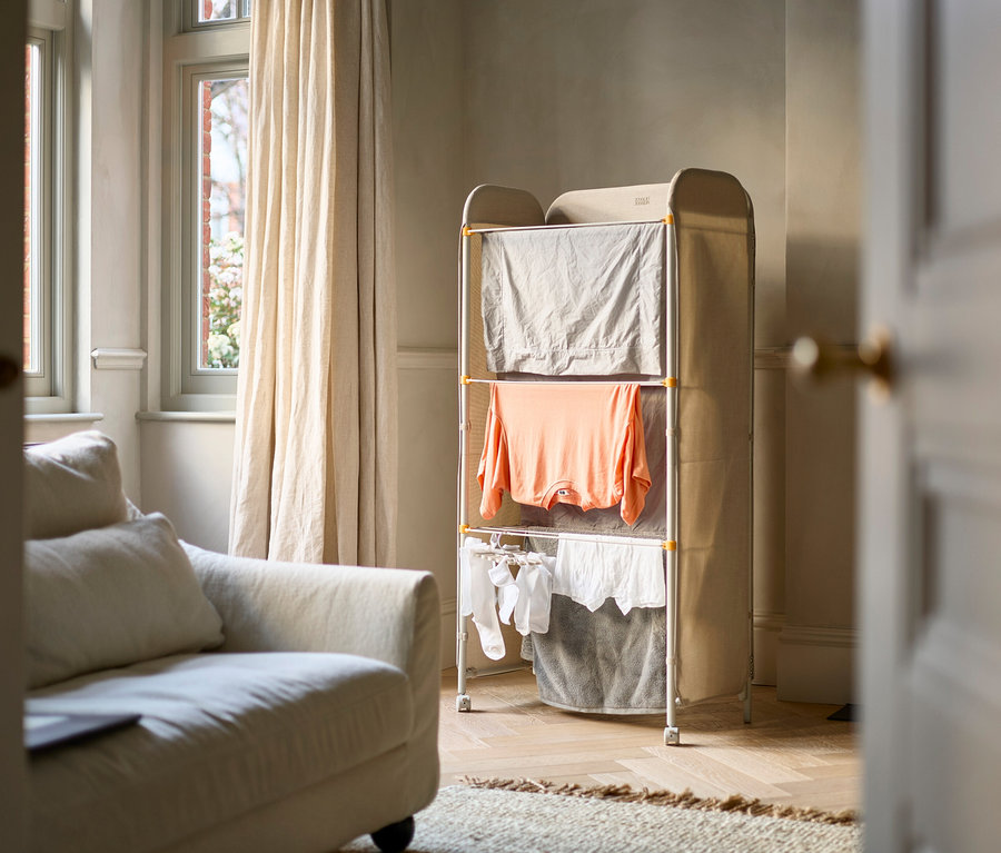 Im Zimmer steht ein Wäscheständer mit Kleidung.
