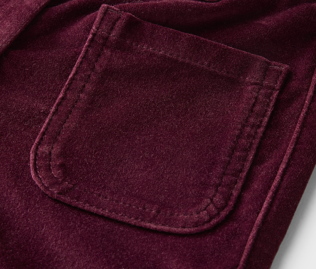 Detailaufnahme einer lilafarbenen Samthose mit Tasche.