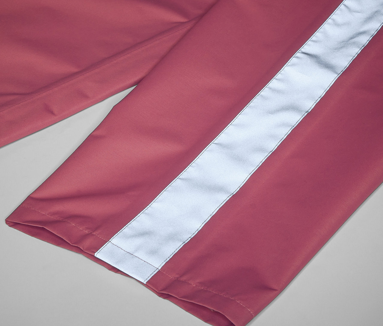 Detailaufnahme einer rosa Kinder-Regenhose mit einem reflektierenden Streifen.