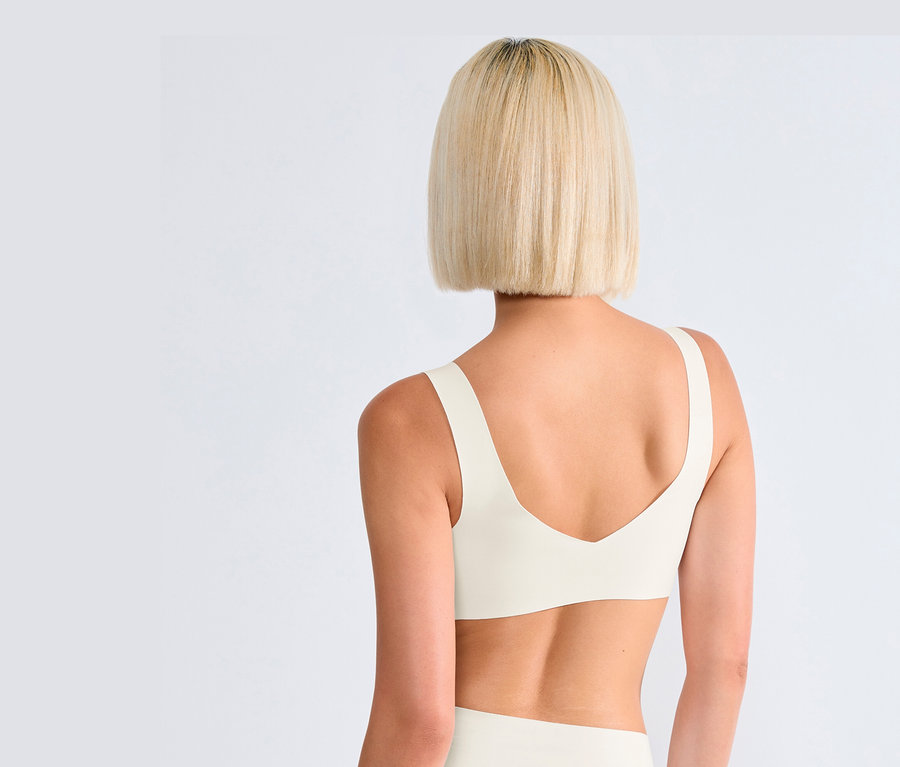 Rückansicht einer blonden Frau, die eine sloggi ZERO Feel 2.0 Bralette in Seidenweiß trägt.