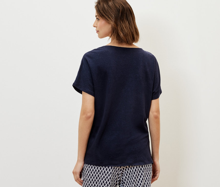 Frau trägt ein marineblaues Shirt aus Leinenmix und gemusterte Hose.