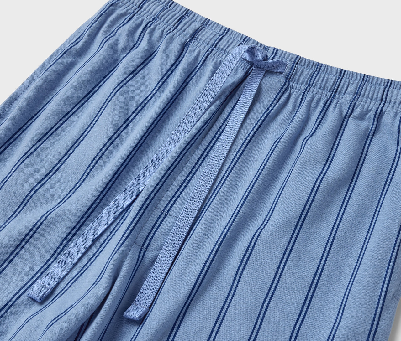 Detail einer blauen, gestreiften Pyjamahose mit Gummibund und Kordelzug.