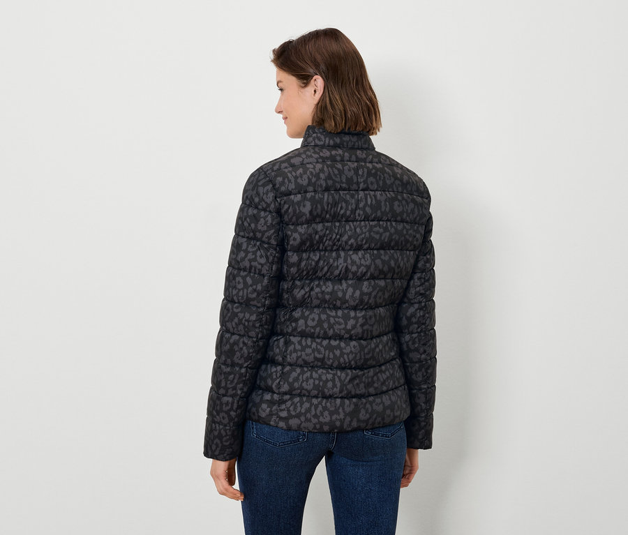 Frau von hinten trägt eine schwarze, tiermustergemusterte Steppjacke und Jeans.