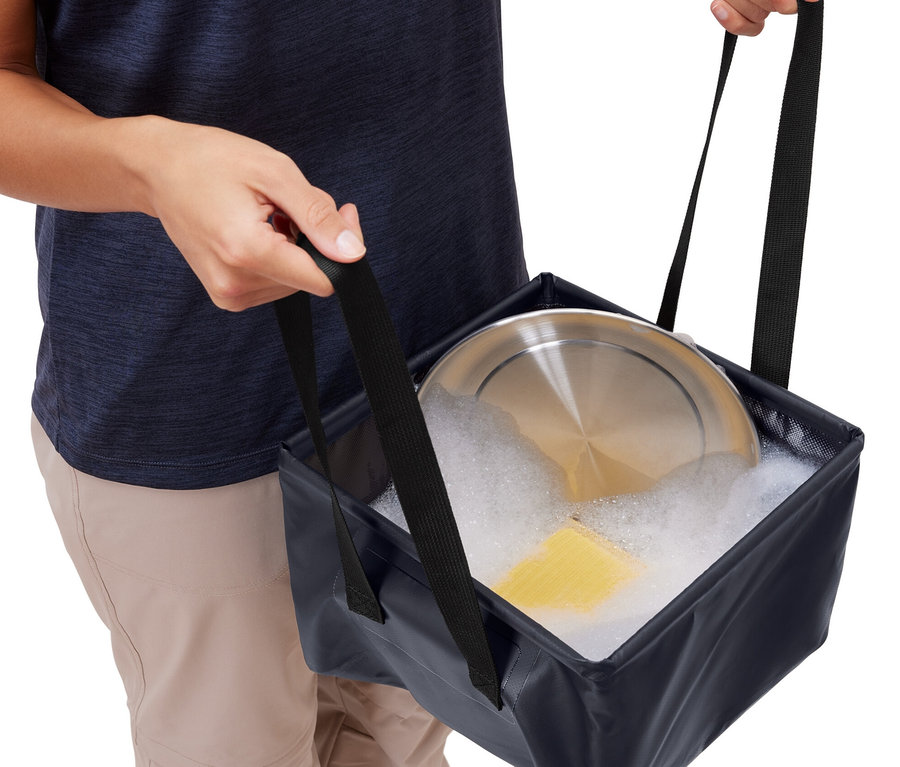 Person hält faltbare Spülschüssel mit Geschirr und Seifenwasser.