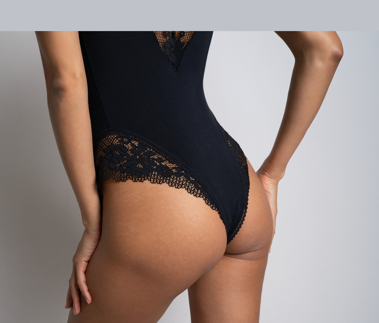 Rückenansicht einer Person in einem schwarzen Passionata Body »Nina« mit Spitzendetails an Rücken und Seiten.
