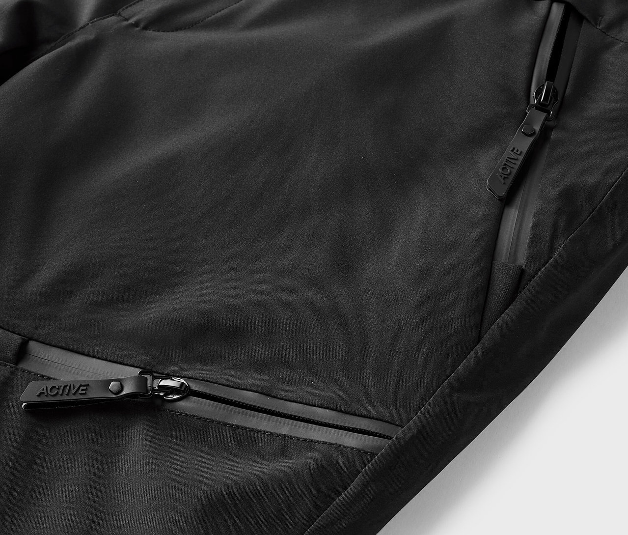 Detailaufnahme von schwarzer Sportbekleidung mit Reißverschlusstaschen.