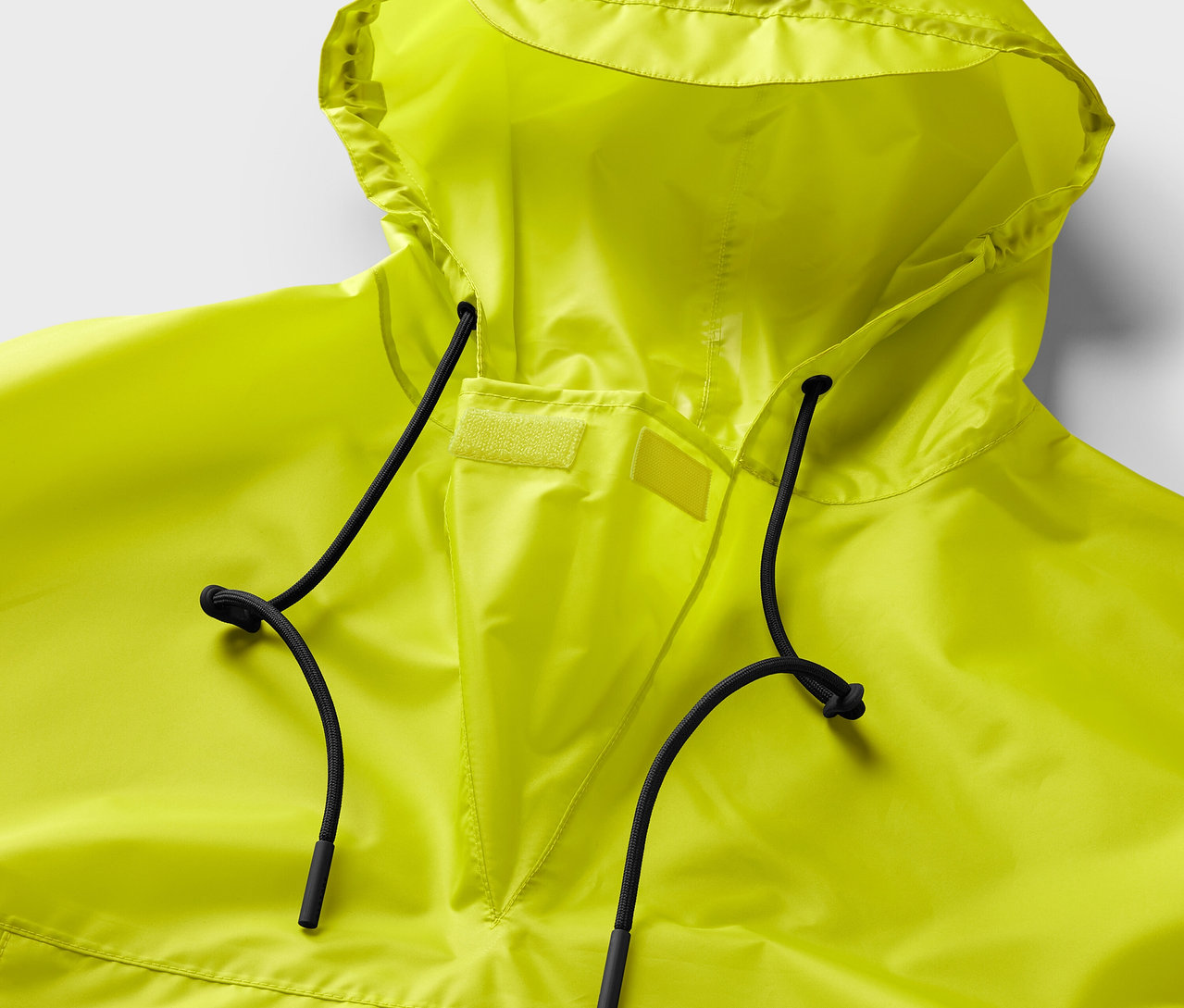 Nahaufnahme eines neongelben Regenponchos mit Kapuze und schwarzen Kordeln.
