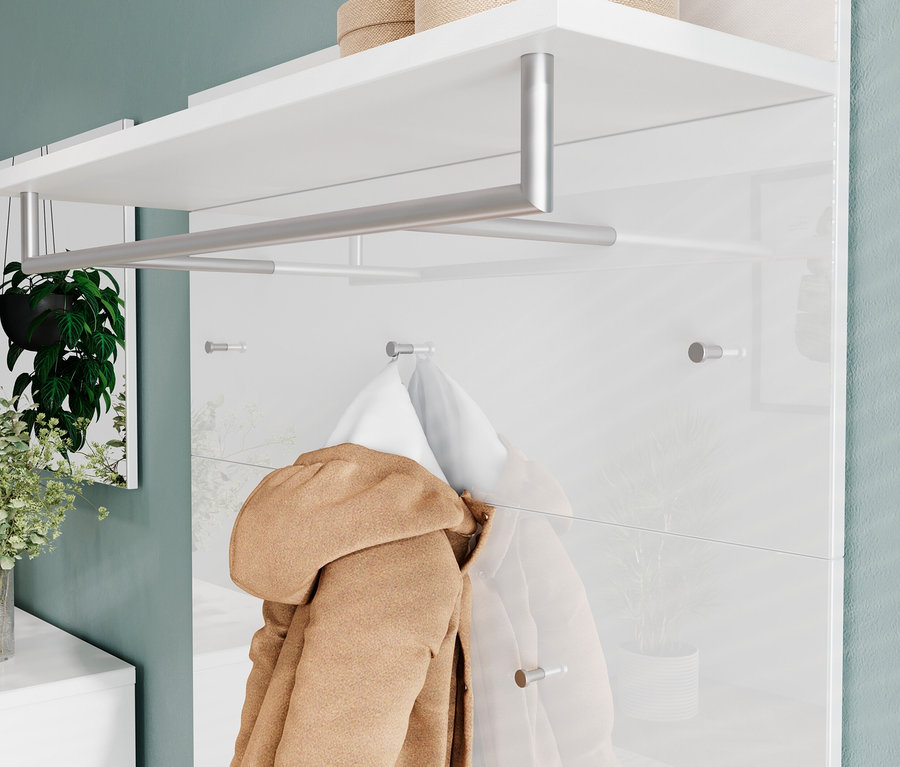 Beige Kapuzenjacke hängt an einer weißen Wandgarderobe mit Regal und Stange; Spiegelung einer Topfpflanze.