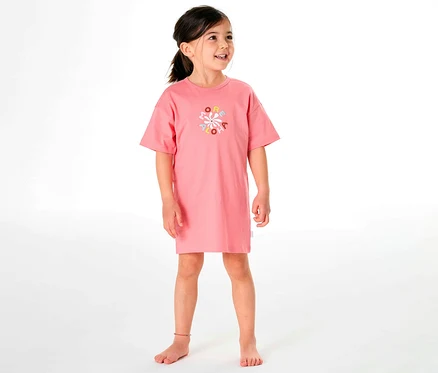 Mädchen trägt ein rosafarbenes SCHIESSER Kinder-Nachthemd mit einem bunten Aufdruck.