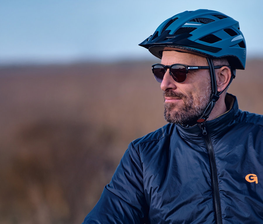 Mann mit Bart und Sonnenbrille trägt einen blauen FISCHER Fahrradhelm Urban PLUS Chicago.