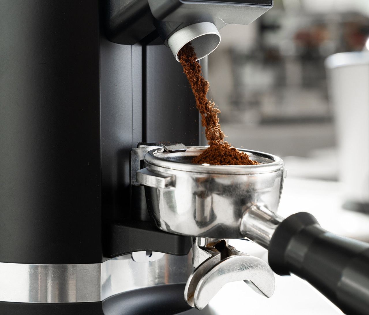 Kaffeepulver wird in einen Siebträger einer Kaffeemühle gefüllt.