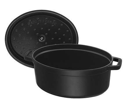 Schwarzer, ovaler Kochtopf mit Deckel, der daneben liegt.