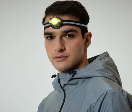 Porträt eines Mannes mit Stirnlampe und grauer Kapuzenjacke.
