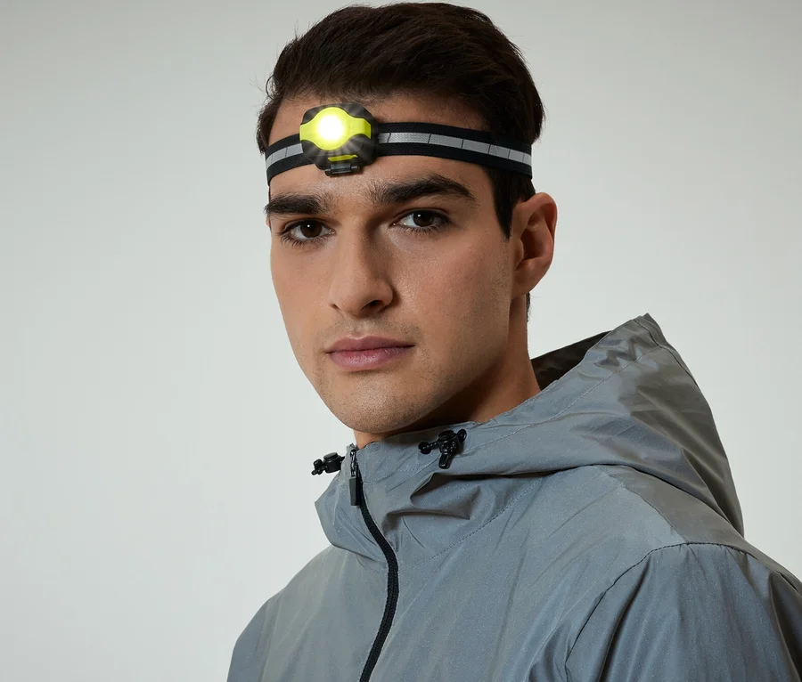 Porträt eines Mannes mit Stirnlampe und grauer Kapuzenjacke.