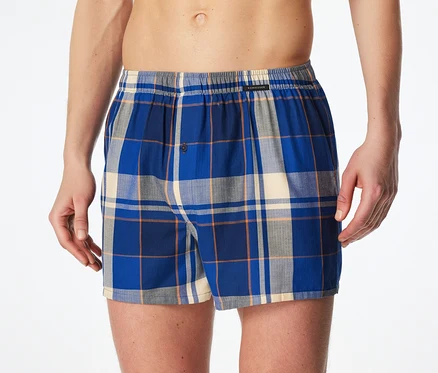 Mann trägt blau-grau-creme-orange karierte Boxershorts mit Gummibund und Knopfleiste.