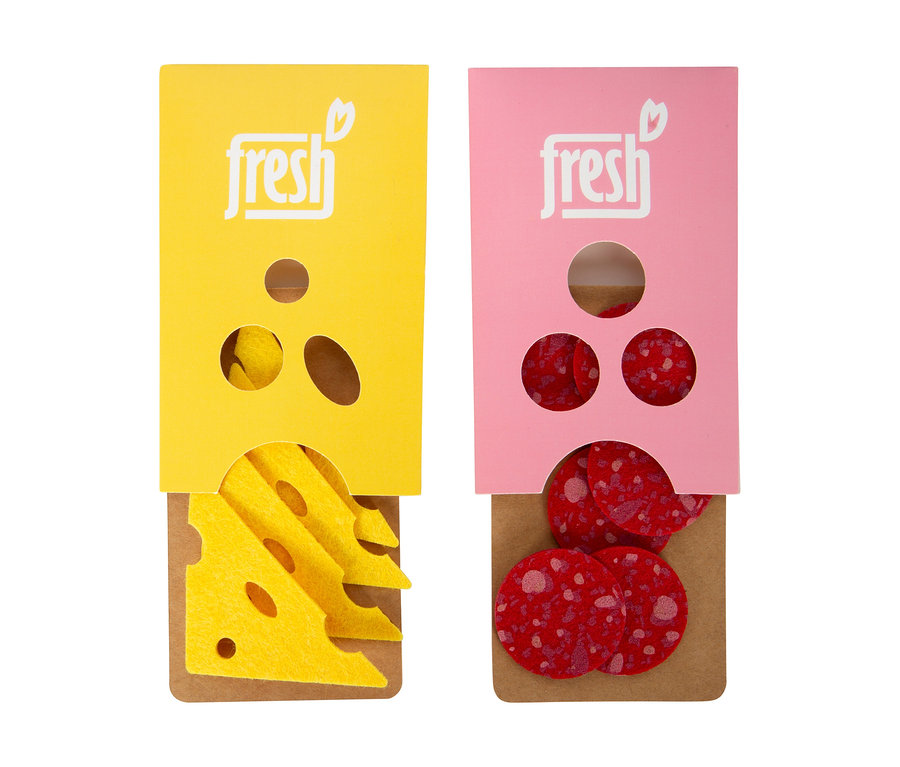 Zwei Spielzeug-Lebensmittelpackungen für einen small foot Kaufladen: eine gelbe mit Filzkäsescheiben und eine pinke mit Filzsalamischeiben, beide mit „fresh“ beschriftet.