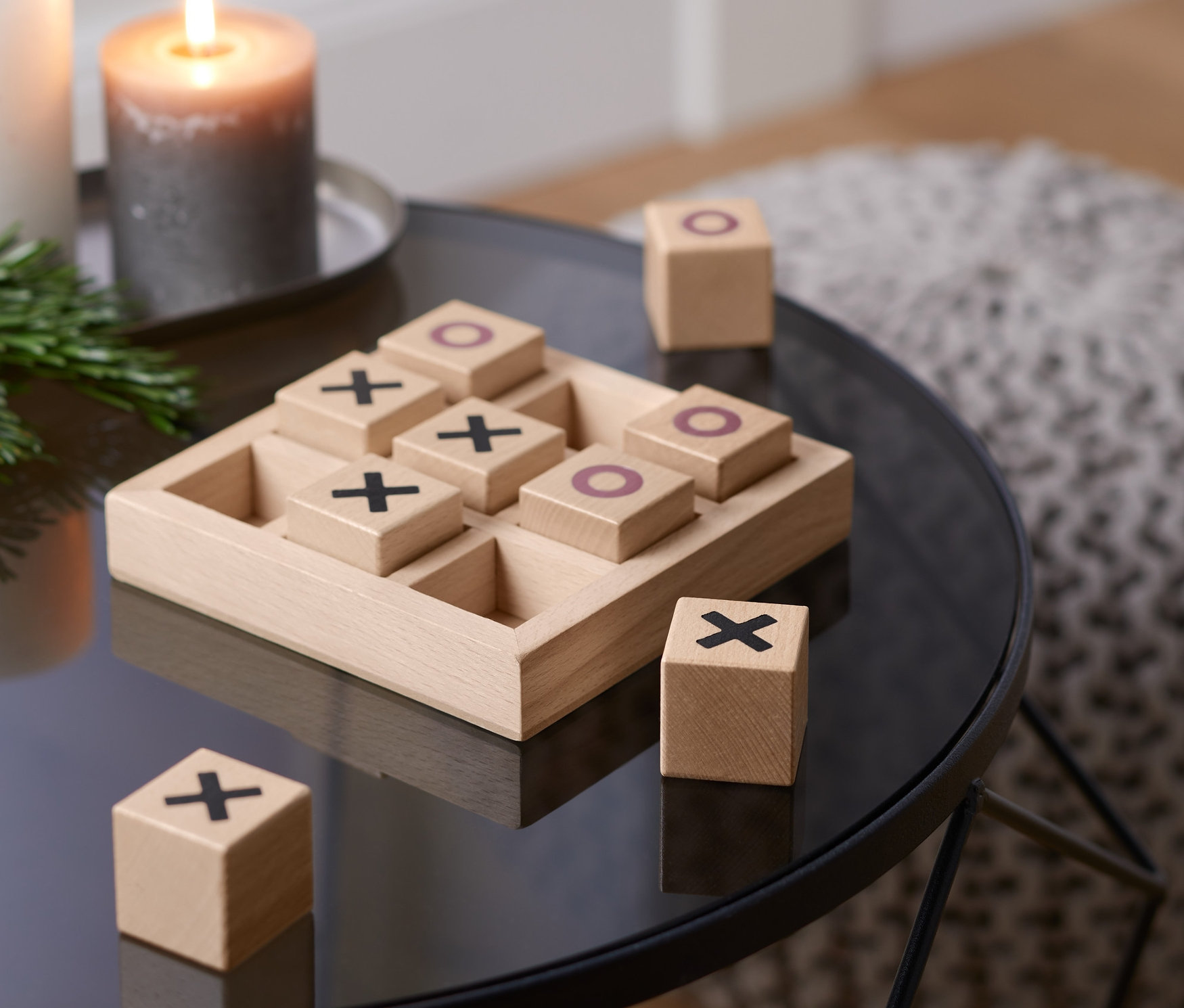 Auf einem Tisch liegt ein Tic Tac Toe Spiel mit Holzwürfeln mit Kreuzen und Kreisen.