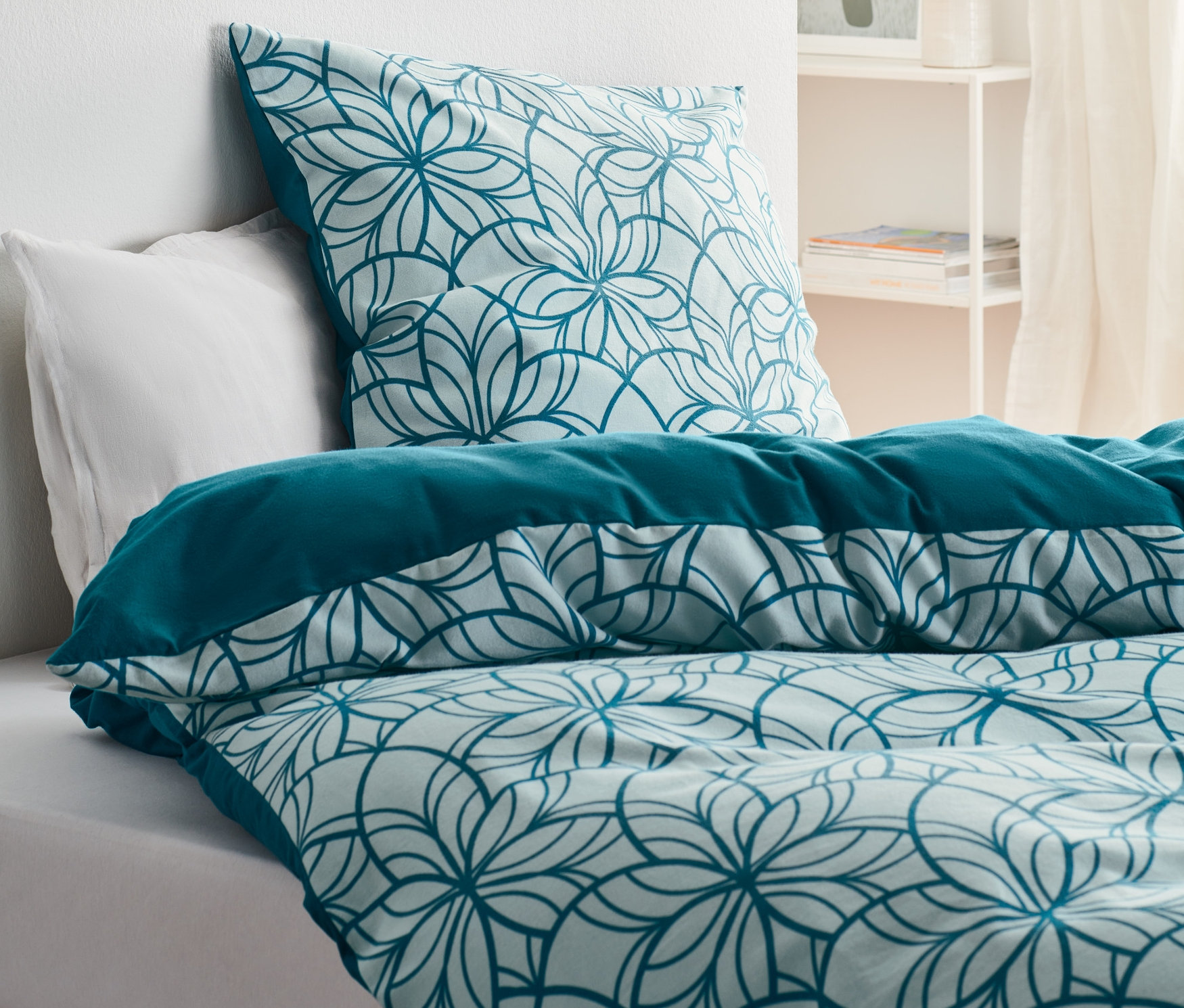 Bett mit Biber-Bettwäsche, Normalgröße, mit Blumenmuster und unifarbenem Rand.