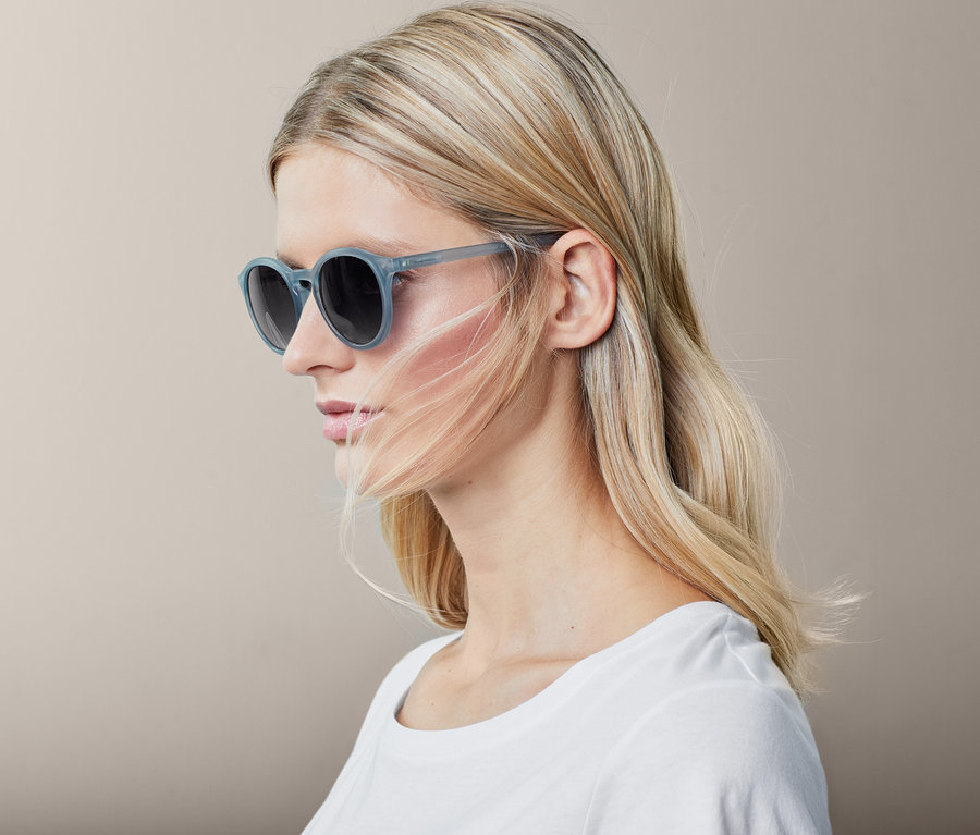 Profil einer blonden Frau mit hellblauer Sonnenbrille.
