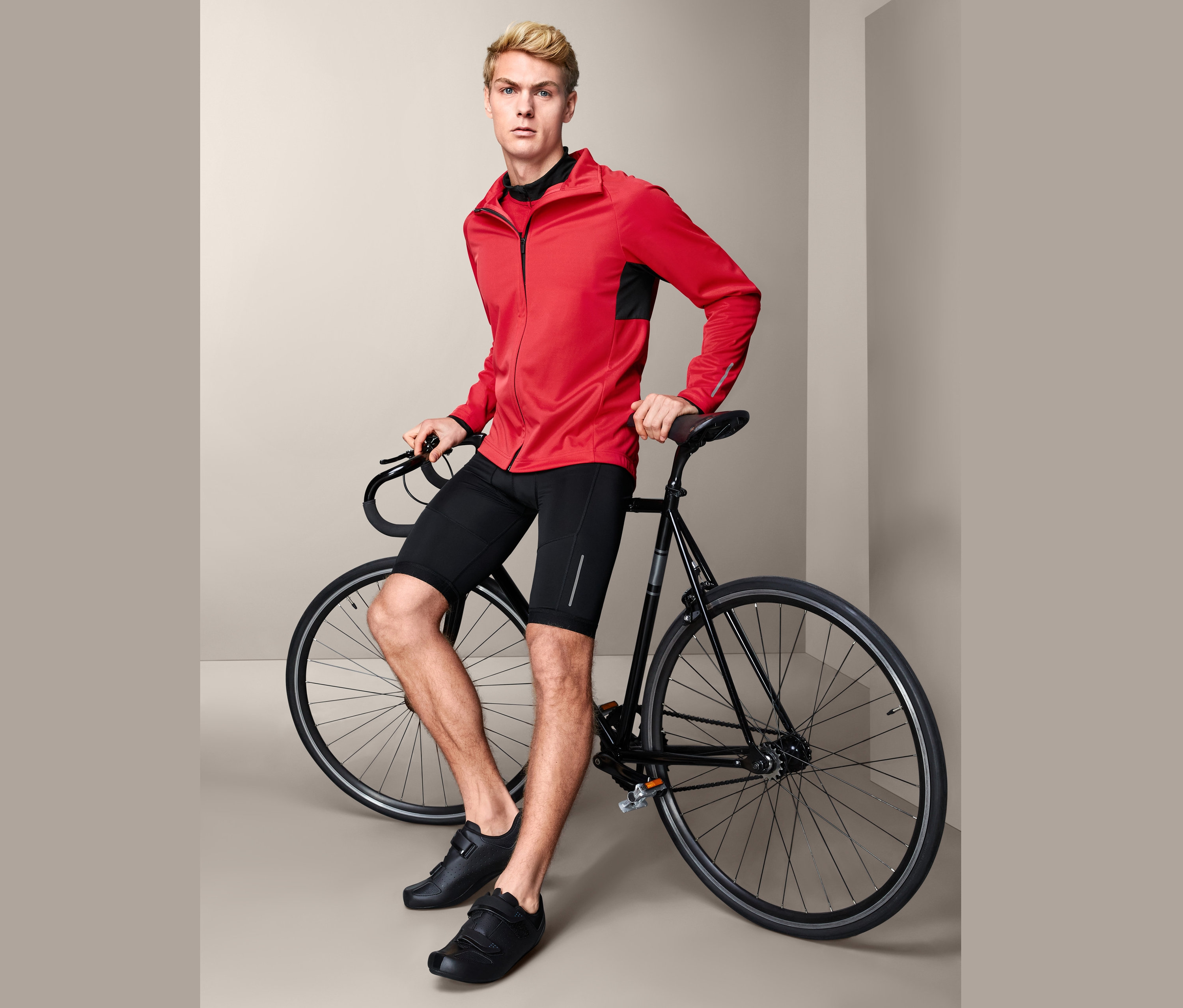 Mann posiert mit Fahrrad und trägt eine Rad-Softshelljacke.
