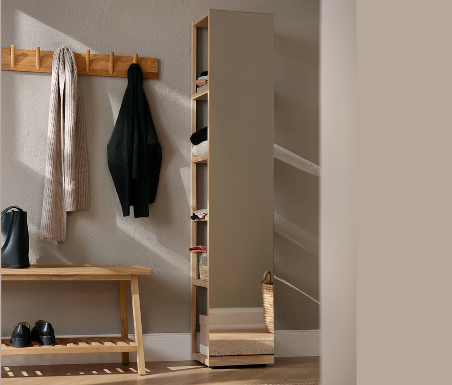 Im Flur stehen eine Sitzbank mit Ablage, Schuhe und eine Handtasche. An der Wand hängen eine Garderobe mit Schal und Jacke.