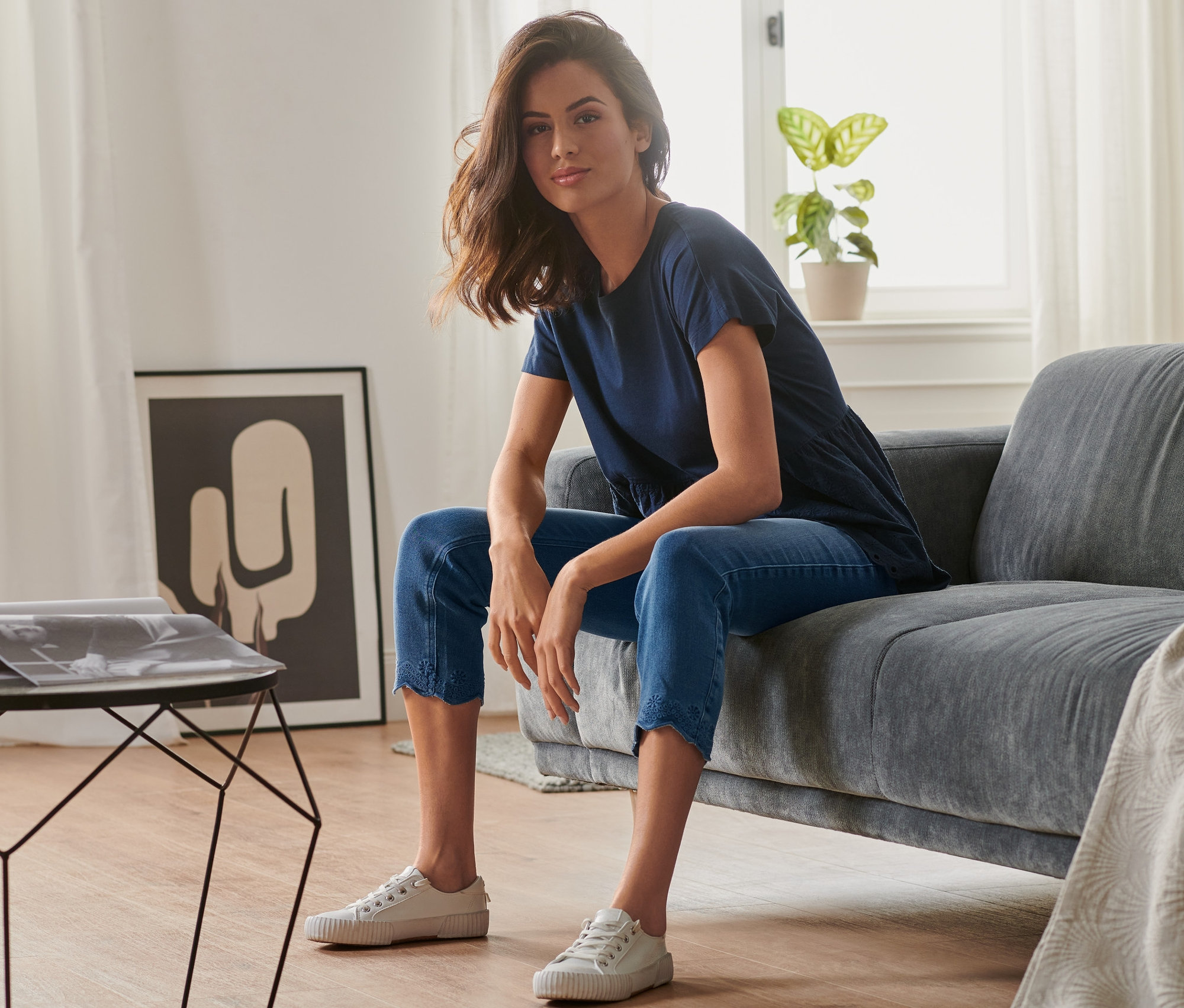 Frau sitzt auf einem Sofa und trägt eine 7/8-Treggings mit Lochstickerei.