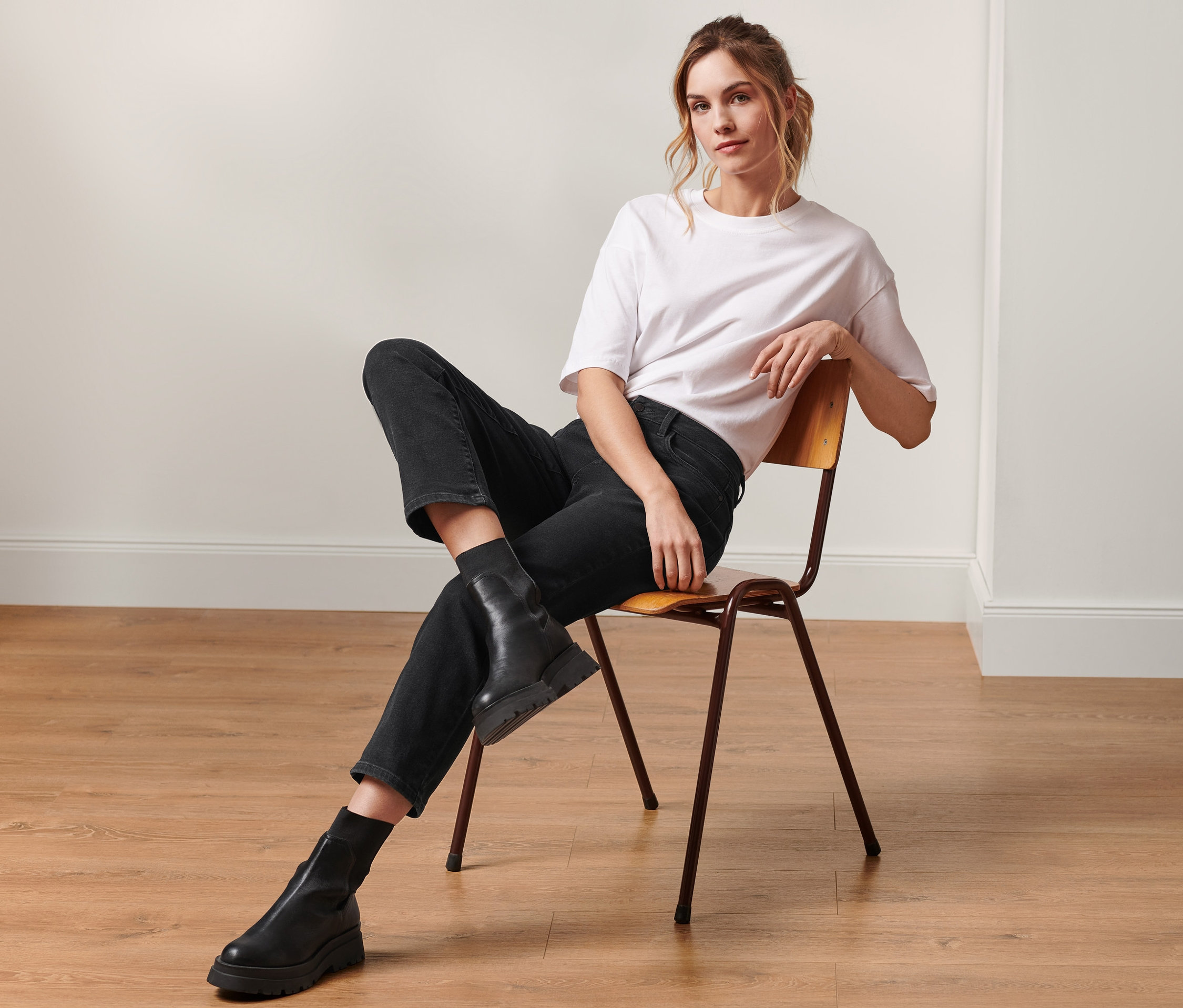 Frau sitzt auf einem Stuhl und trägt eine Cropped-Denim »Fit Alma«.