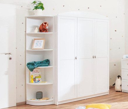 Ein weißes Pinolino Eckregal steht neben einem weißen Kleiderschrank und einer weißen Kommode in einem Kinderzimmer.