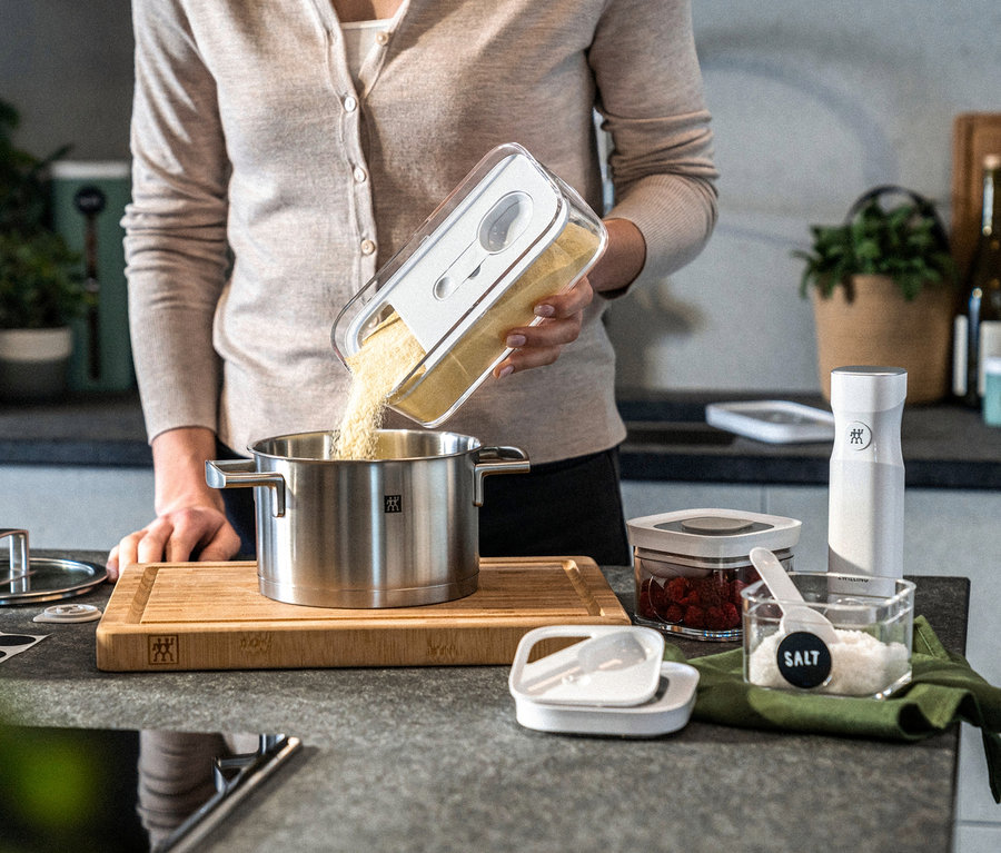 Frau schüttet Inhalt aus ZWILLING FRESH & SAVE CUBE Vakuum-Box-Set in Kochtopf.