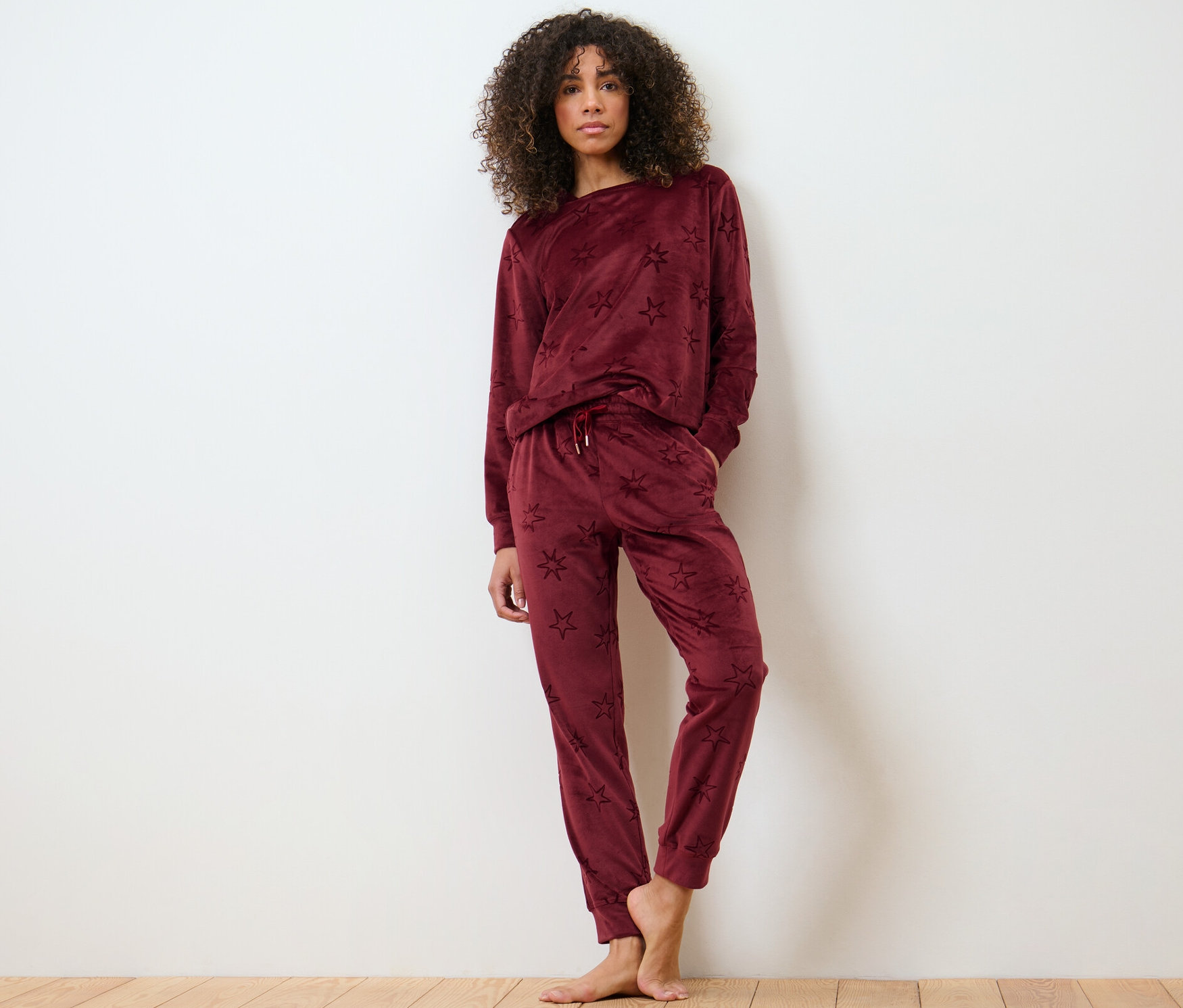 Frau posiert auf Holzboden im Nicki-Hausanzug.