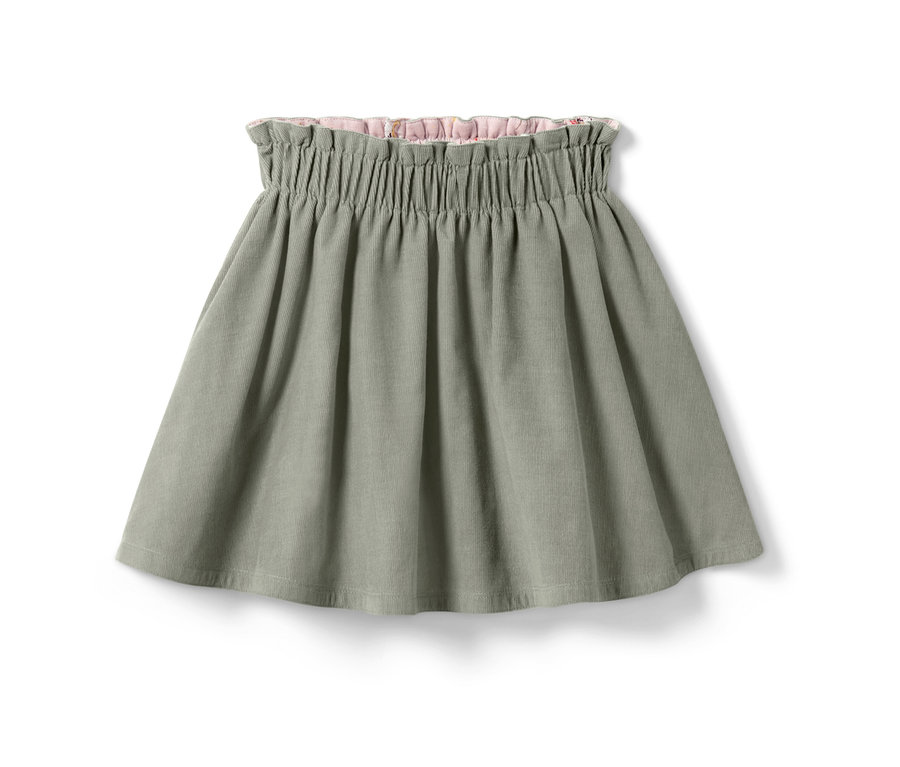 Ein grüner Kinder-Cord-Wende-Rock mit einem floralen Muster auf der Innenseite.