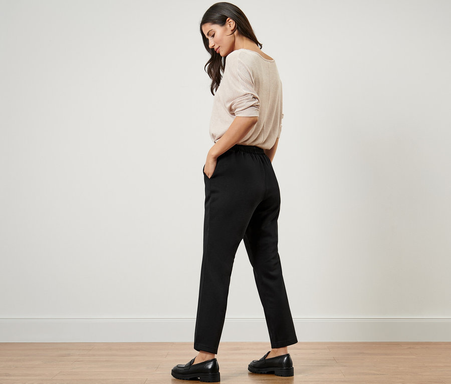 Frau mit Händen in den Taschen der schwarzen Joggpants.