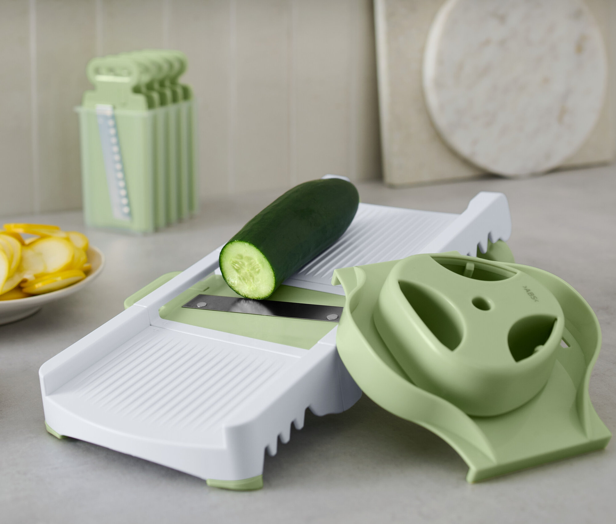 Gurke liegt auf Multireibe. Daneben liegen geschnittene Gurken und Zucchini.