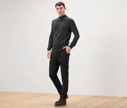 Ein Mann posiert in einer schwarzen Comfort-Stretch-Hose für die Kamera.