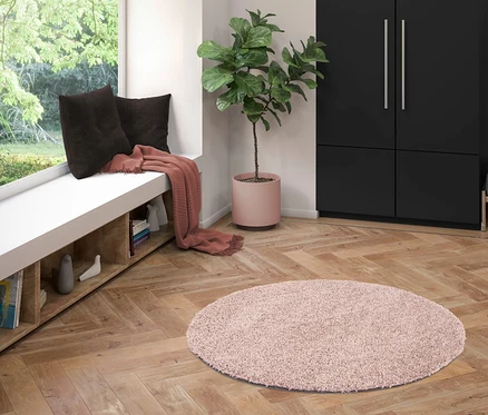 Ein pinker Teppich »Charme« liegt auf dem Parkettboden im Wohnzimmer.