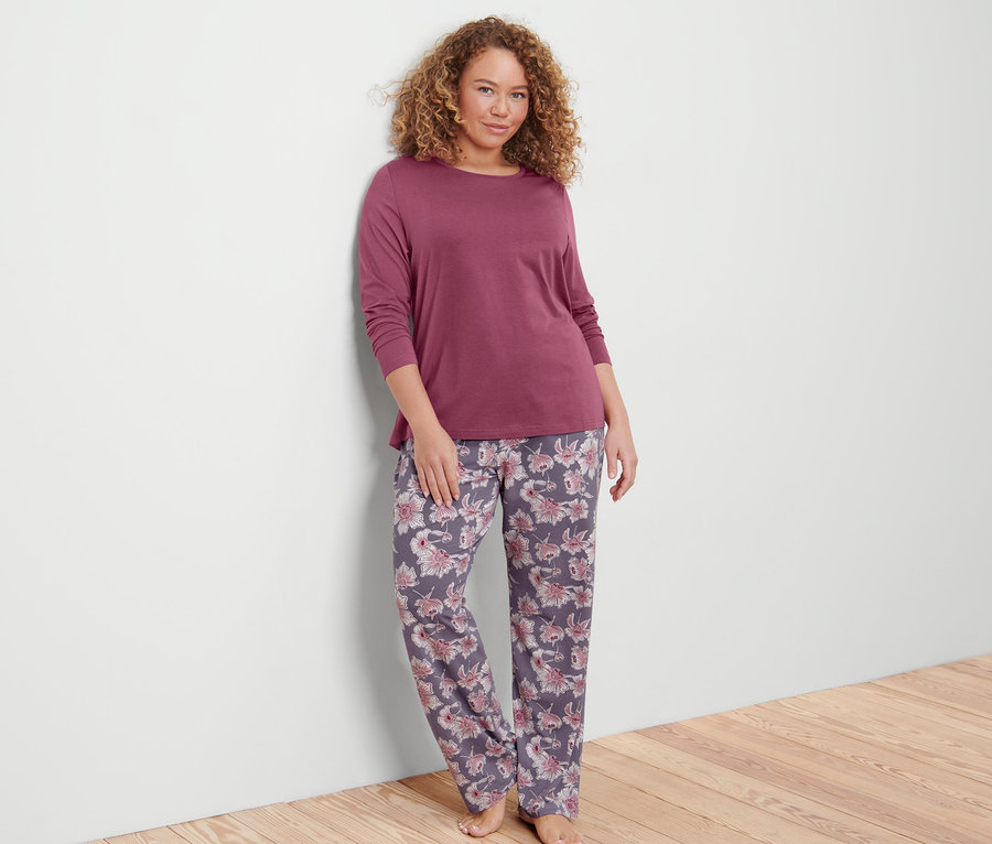 Frau an Wand angelehnt trägt einen Pyjama.