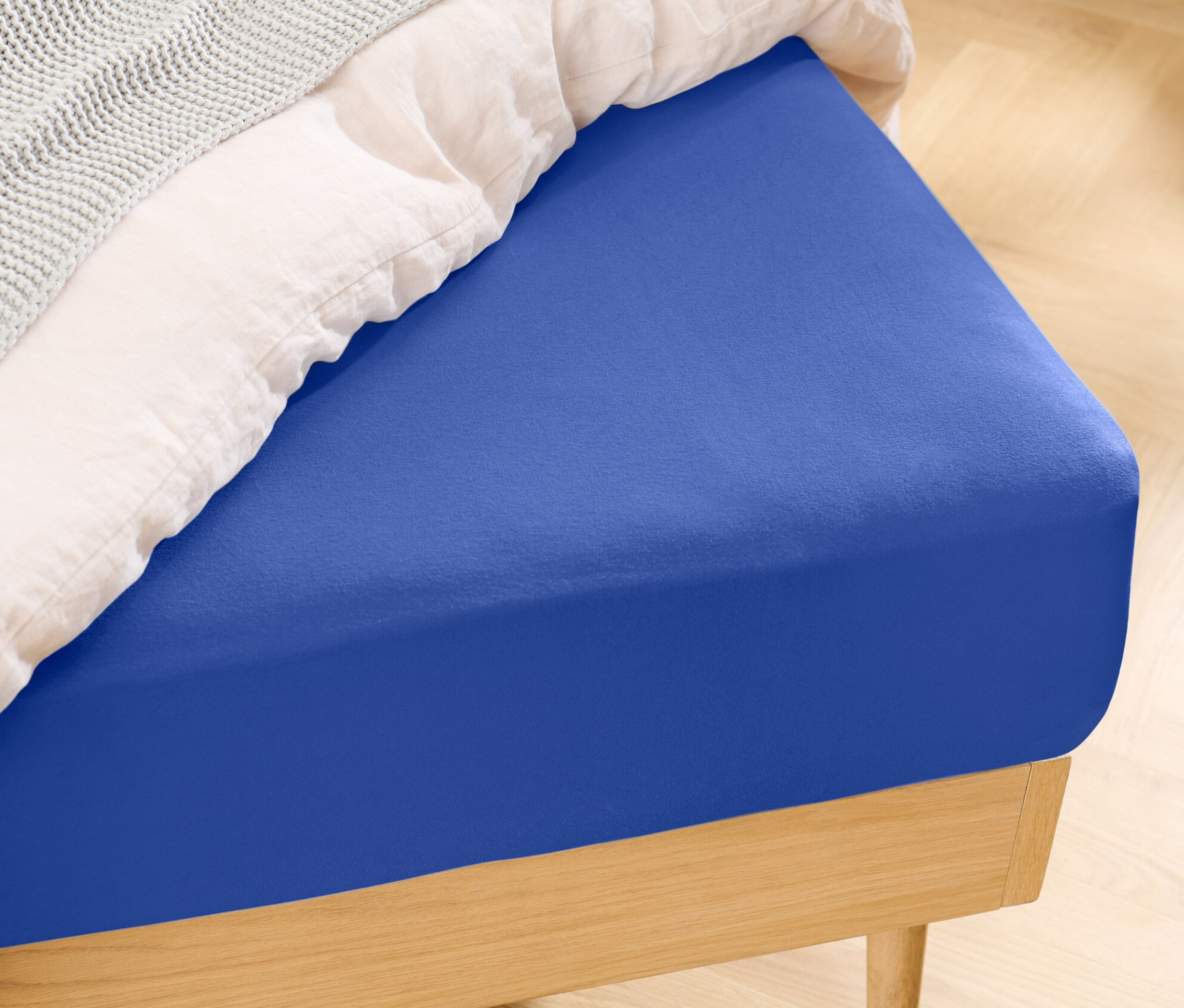 Bett mit blauem Jersey-Spannbettlaken.