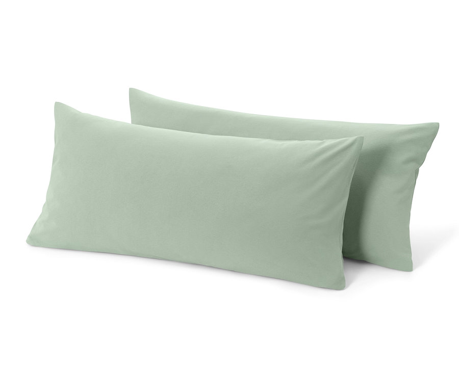 Zwei salbeigrüne Jersey-Kopfkissenbezüge liegen übereinander.