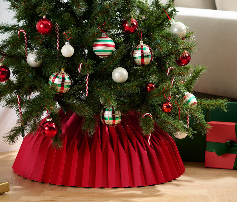 Weihnachtsbaum geschmückt mit Ornamenten und Zuckerstangen, stehend auf einem Papier-Weihnachtsbaumrock.