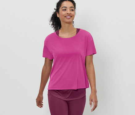 Frau trägt ein pinkes 2-in-1-Kurzarm-Sportshirt und geht.