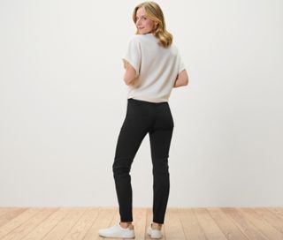 Frau blickt über die Schulter und trägt eine schwarze Stretchhose.