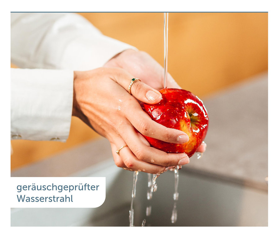 Frau wäscht einen roten Apfel unter fließendem Wasser. Schütte AQUASTAR PRO Filterarmatur, black.