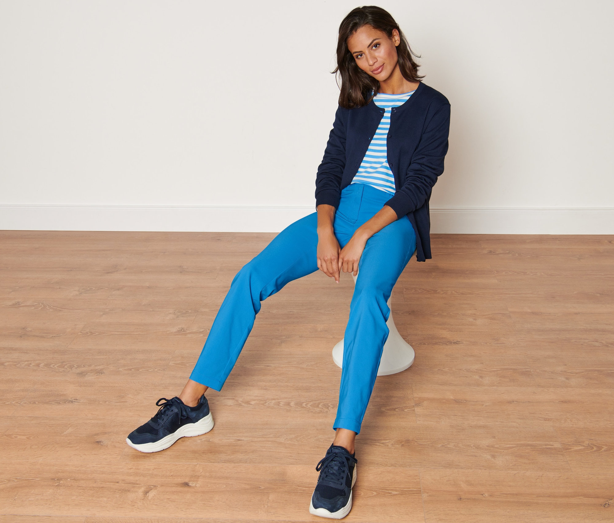 Frau sitzt auf einem Hocker und trägt eine blaue Bengalin-Hose.