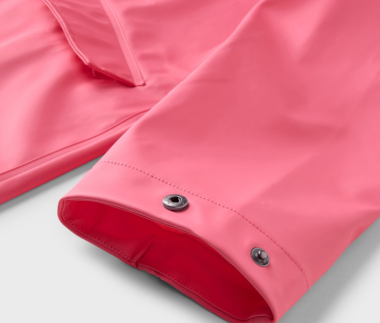 Detailansicht eines pinken Regenmantels mit Druckknöpfen.