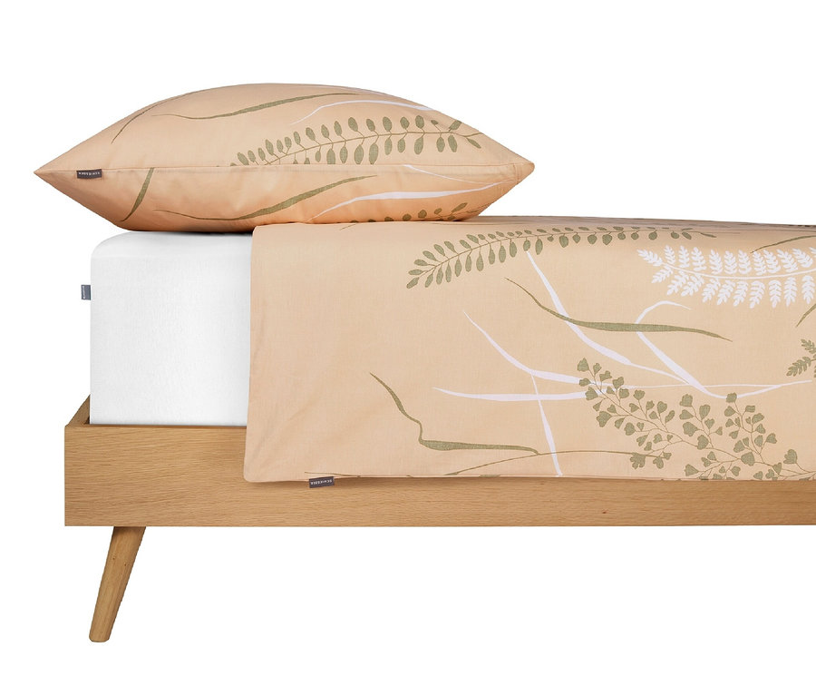 Beige Bettwäsche mit Pflanzenmuster auf einem Bett mit weißem Spannbettlaken und Kissen.