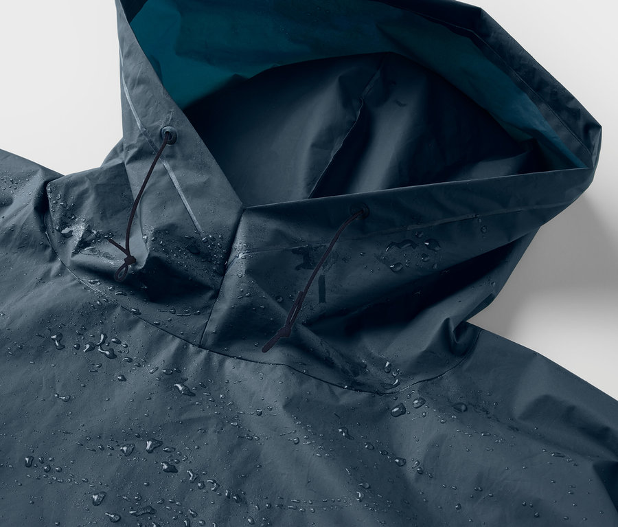 Detailaufnahme der Kapuze eines blauen Regenponchos mit Wassertropfen.